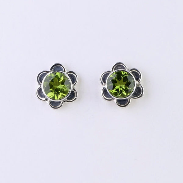 A faceted round lime green peridot stone forms the centre of the flower - about two thirds of the total size. This is surrounded by six small oxidized silver petals, with polished edges, equally spaced around.