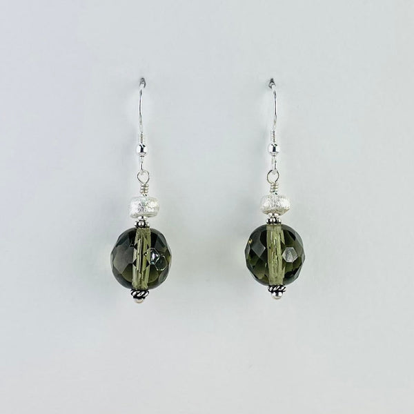 Round faceted olive colour vintage glass bead is set below a much smaller satin finish bead attached to a silver hook.                                                