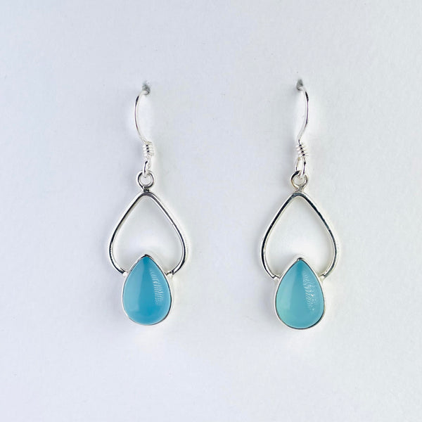 tear drop shaped, opaque blue coloured chalcedony stone is set at the bottom of a larger tear drop shaped silver shape. all set below a silver hook.