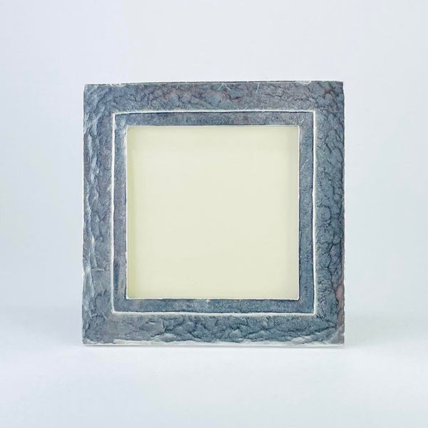 A square pewter photograph frame, in a grey colour, with a delicately hamm look finish . The inner opening is framed with a single line in a polished pewter finish about half a centimeter in.