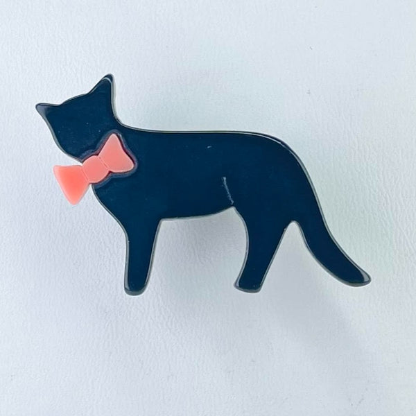 A simple cat shape with a tail and its face turned towards you, ears up. It is sporting a large pink bow around its neck.