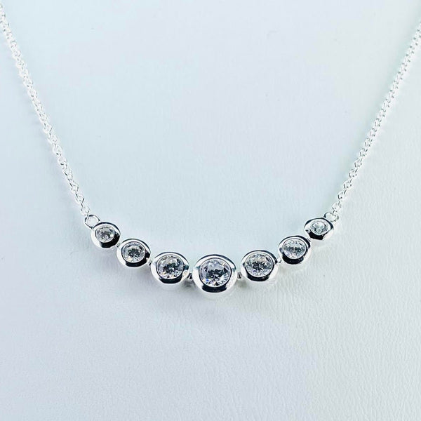 7 round sparkly cubic zirconia stones, set in silver, are arranged in a gentle curve around the front of the necklace. They get larger as they get to the front with the central one at the front being the biggest . The three on each side mirror each other in size. Attached to a silver link chain by small silver rings.