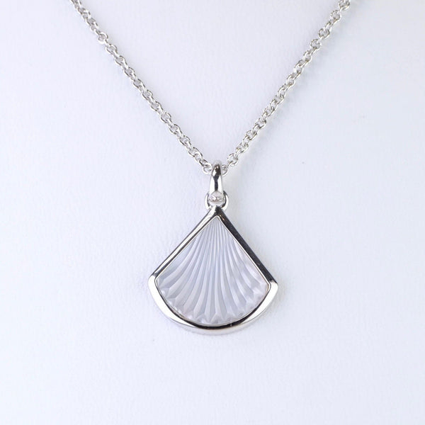 A fan shaped piece of mother of pearl is framed in shiny silver. The  mother of pearl had been carved so that it looks like an open fan with folds in it. The pattern hangs on a link chain, with a plain silver bail.