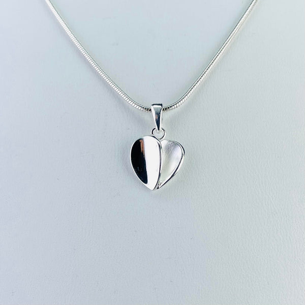 A little heart pendant, one half is satin silver, the other is shiny. Very simple, with a plain silver bail on a snake chain.