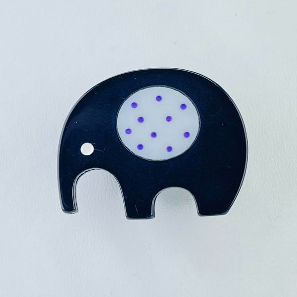 A simple shape of an elephant, a bit like a child would draw ! It has a black body with a white eye and a decorated disc in the middle which is grey with blue spots.