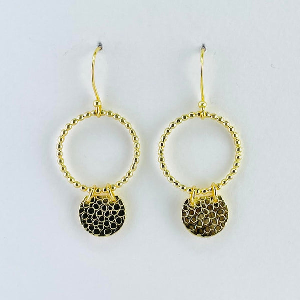 Gold plated earrings formed of two circles. The top, larger circle is an outline made of 33 little bean shaped blobs. The lower, much smaller circle is a solid shaped with a scale pattern engraved on to it. Attached to the top by two gold coloured jump rings . They have a gold  hook at the top.