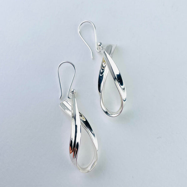 Highly polished silver is folded over on its self with a vertical drop. It looks just like half a bow with the silver hook simply attached at the top.