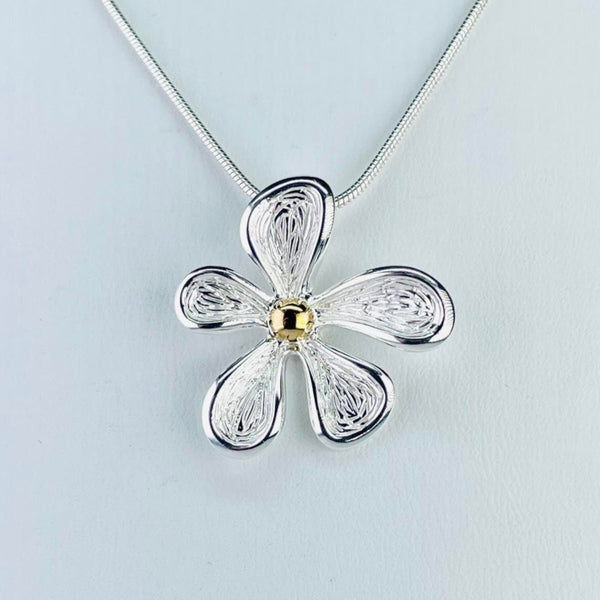 A flower pendant with 5 textured silver petals. They are all a similar rounded edge shape with a high polished edging, but are slightly different sizes. The centre of the flower has a gold plated dot. The chain threads through the back and is gold plated.