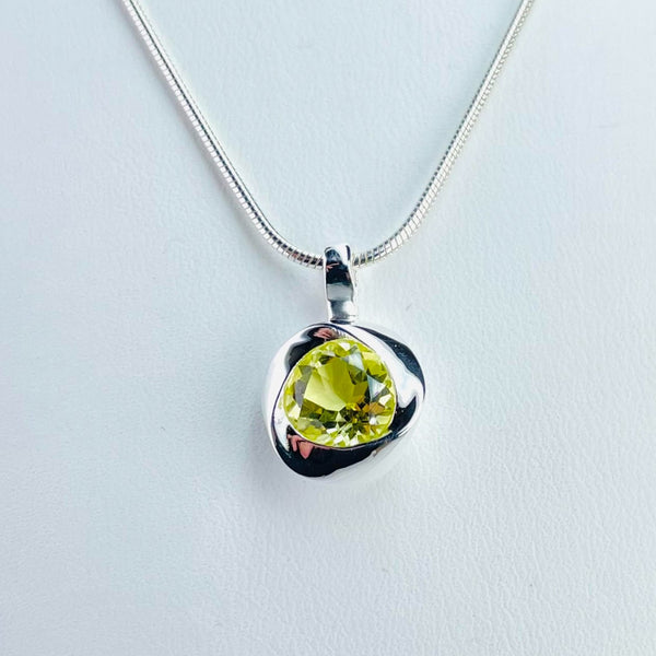 Lovely lemon coloured faceted sparkly stone is framed with smooth shiny silver in an almost triangle twisted shape with a round centre. It has a plain silver bail and is on a snake chain.