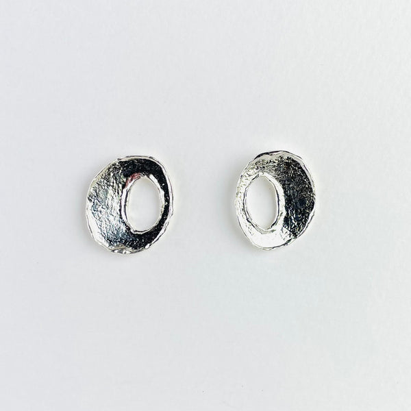 oval shaped earrings with a rough silver texture. They have an oval outline with an oval cut out in the centre.