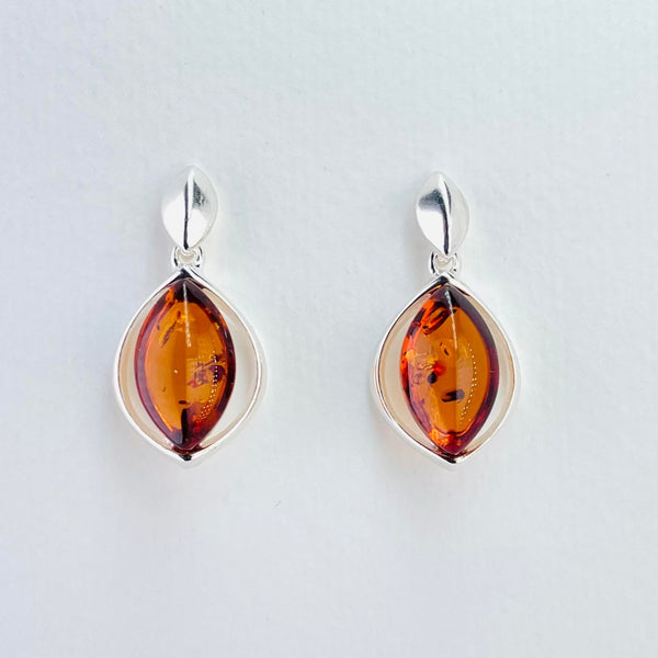 Earrings formed of two parts, the top part is a small silver leaf with a central ridge. Below this hangs a marquise shape, much bigger than the leaf. This is a polished silver outline with an inner marquise shaped piece of amber, deeper in the middle than the edges. The amber is bright deep orange with interesting uneven occlusions within it.