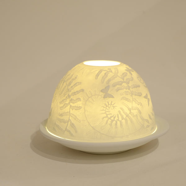 white dome shaped tea light holder, lit from inside by a tea light,decorated by fern leaves and butterflies