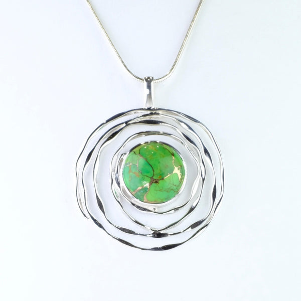 Fairly large pendant formed of a spiral of silver, with uneven thickness, surrounding a bright green round mojave turquoise stone. The stone has stripes and flecks of gold randomly spread throughout it.